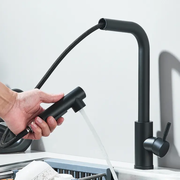 Person using a black pull-out kitchen faucet over a sink.