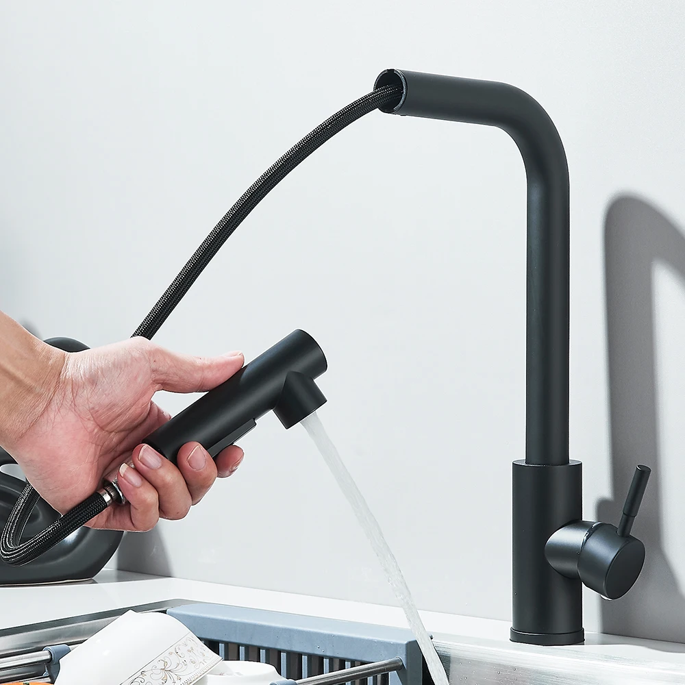 Person using a black pull-out kitchen faucet over a sink.