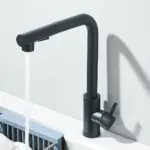 Modern black kitchen faucet with water flowing into a sink.