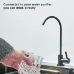 Hand holding a glass under a modern black faucet with water flowing.