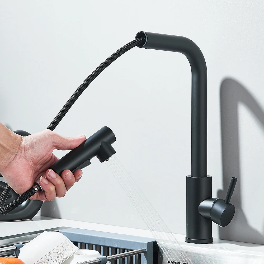Person using a black pull-out kitchen faucet over a sink.