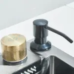 Modern kitchen sink with gold faucet handle and black soap dispenser.